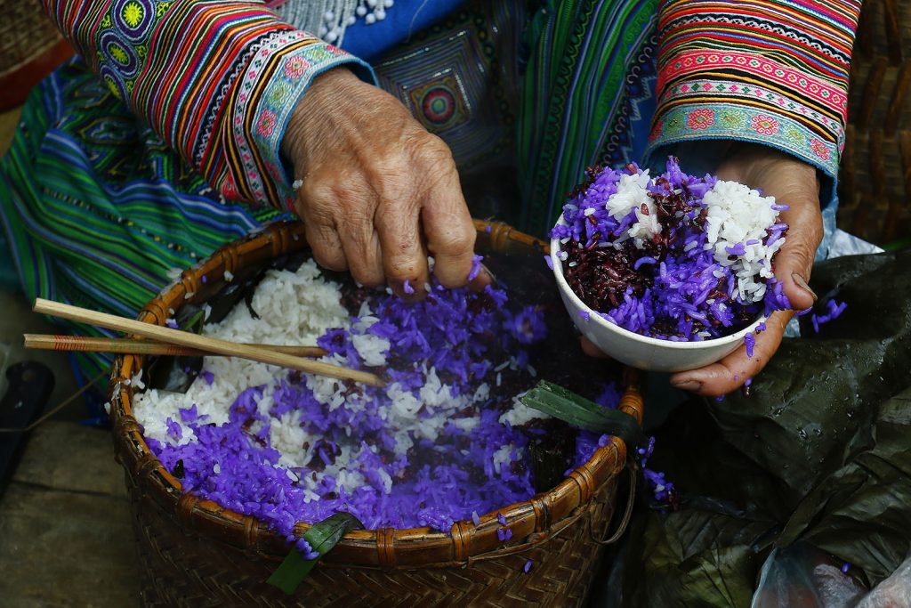 Woman in Thailand putting purple and white rice into a bowl